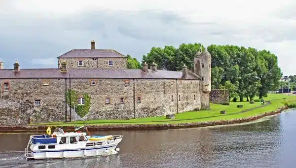 Enniskillen castle by the water with a riverboat passing by
