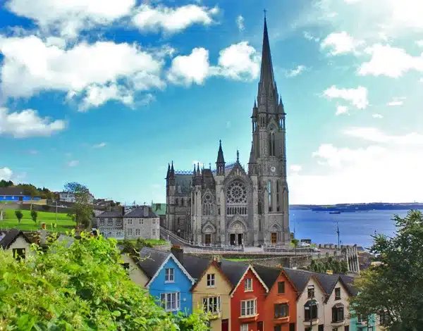 Cobh Cathedral with row of colourful houses in front of it on a sunny day