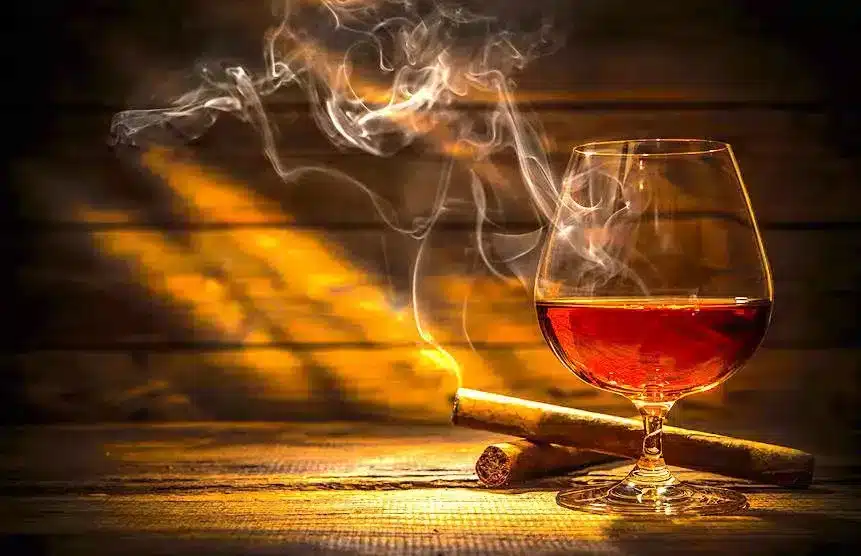 54094133 - glass of whiskey with smoking cigar and ice cubes on wooden table