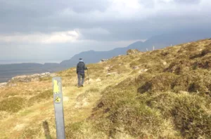 Irish pilgrim path through hills with woman hiking
