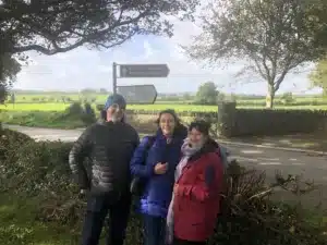 An Irish road to Monasterboice with Mike, Carina and Jayne standing in front of hedgerow