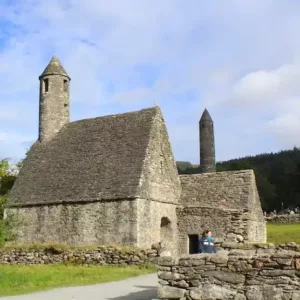 Irish church in stone with a round tower and old stone walls.