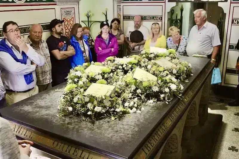 Daniel O'Connell tomb in Glasnevin cemetery Ireland, covered in flowers and surrounded by people