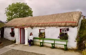 An Irish cottage with a thatch roof, whitewashed walls and flowers in the windows at Doagh famine village.