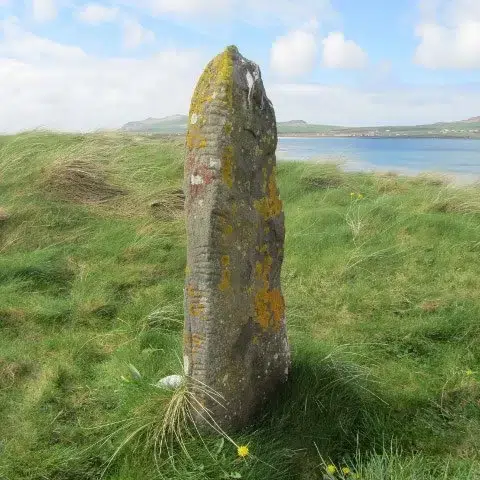 Ogham Stones: Run Your Hand Across a Piece of History 1 Ancient ogham stone in a green field looking out at the sea